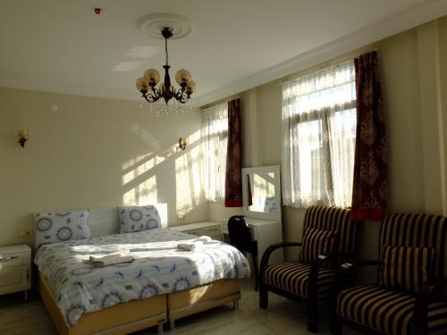 a bedroom with a bed and two chairs and a chandelier at Old City Pansiyon in Istanbul