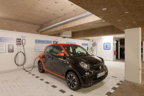 een kleine auto wordt opgeladen in een tankstation bij Designhotel + CongressCentrum Wienecke XI. in Hannover