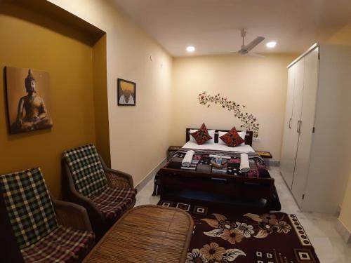 a bedroom with a bed and two chairs and a table at Swiss House in Jodhpur