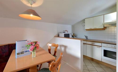 a kitchen with a wooden table with flowers on it at APARTMENTS Pension Foidl in Oberndorf in Tirol