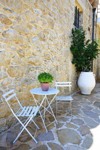 a table and two chairs sitting next to a stone wall at Villa Radamanthis in Sívas