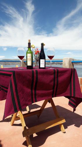 uma mesa com duas garrafas de vinho e dois copos em Amantani Lodge em Ocosuyo