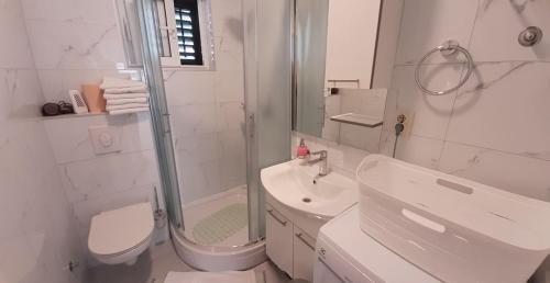a white bathroom with a toilet sink and a shower at Apartments Villa Ravlić in Makarska