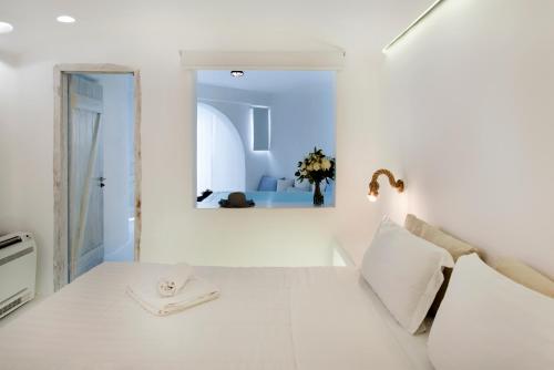 a white room with a bed and a mirror at Zefi Hotel & Suites in Naousa