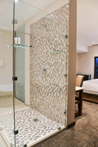 a shower with a glass door in a bedroom at Premier Resort Sani Pass in Himeville