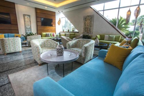 een woonkamer met een blauwe bank en stoelen bij La Casa Hotel Amman by FHM in Amman