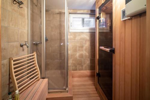 ein Badezimmer mit einer Dusche mit einer Bank und einer Glastür in der Unterkunft Les Trois Voiliers - mit Sauna in Juist