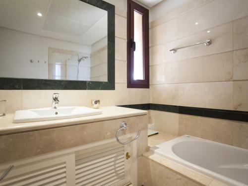 ein Badezimmer mit einem Waschbecken, einer Badewanne und einem Spiegel in der Unterkunft GRAN BAHIA de Marbella in Marbella