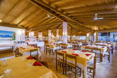 a dining room with tables and chairs with white tablecloths at TH Gioiosa Mare - Capo Calavà Village in Gioiosa Marea