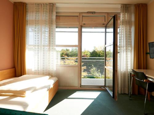 Habitación de hotel con cama y ventana en Sportschule Oberhaching, en Oberhaching