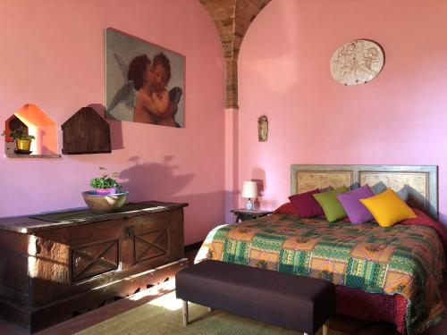 a bedroom with pink walls and a bed and a dresser at Podere Casato in Montespertoli