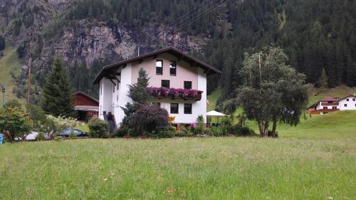a white house with flowers on the side of a field at Mooshof in Kaunertal