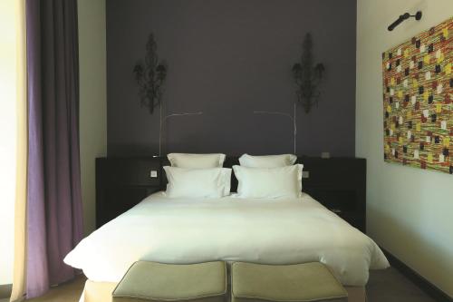 a bed with white sheets and pillows in a bedroom at Domaine De Manville in Les Baux-de-Provence