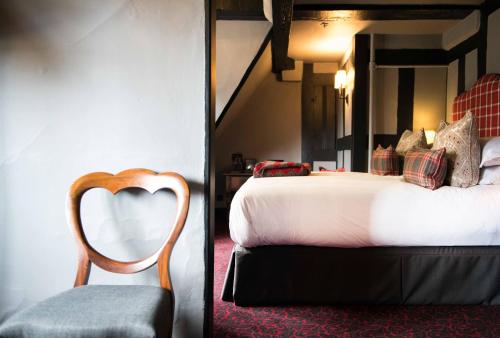 a hotel room with a bed and a chair at The Lygon Arms - an Iconic Luxury Hotel in Broadway