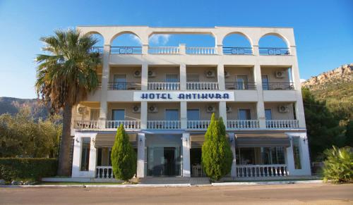 a hotel with a palm tree in front of a building at Antikyra Beach Hotel in Antikyra