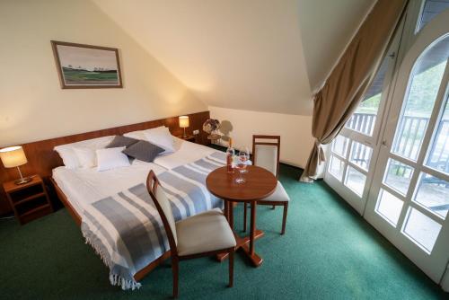 um quarto com uma cama e uma mesa com cadeiras em Zsanett Hotel em Balatonkeresztúr