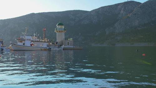 a boat in a body of water with a lighthouse at Antikyra Beach Hotel in Antikyra