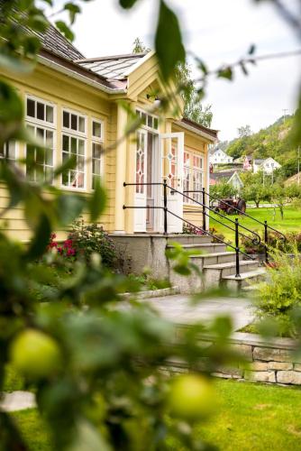 a yellow house with stairs and a porch at Walaker Hotel in Solvorn