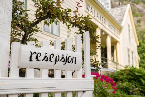 a white fence in front of a house with a registration sign at Walaker Hotel in Solvorn