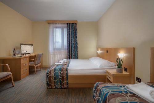 a hotel room with two beds and a desk at Hotel Malovec in Divača