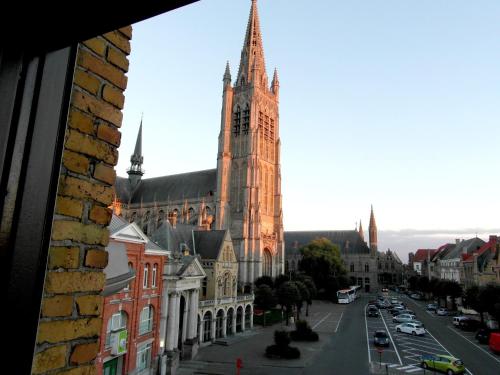 a large church with a clock tower on a city street at Holiday Home Alice House in Ieper