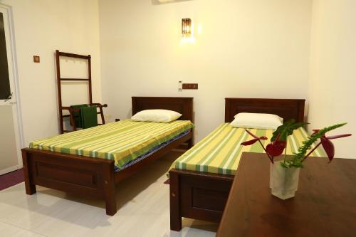 a bedroom with two beds and a table with a plant at Dearly Holiday Home And Safari in Tissamaharama