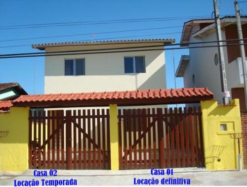 ein gelbes und weißes Gebäude mit einem Tor davor in der Unterkunft Casa Arejada, bem localizada para Temporada em Caraguatatuba in Caraguatatuba