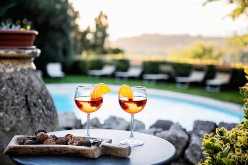 two glasses of wine on a table near a pool at Hotel Villa Gli Asfodeli in Tresnuraghes