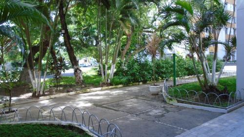 a park with palm trees and a building and a sidewalk at Propriedade aconchego de família in Salvador