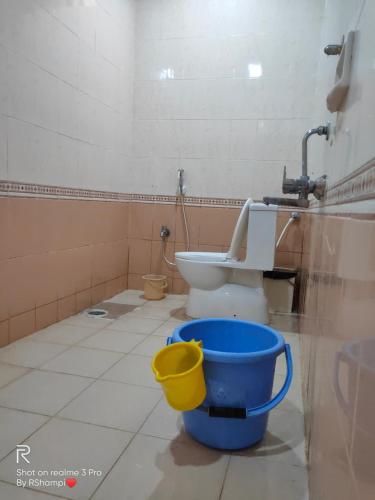 a bathroom with a toilet and a bucket at Manasa guest House in Hampi