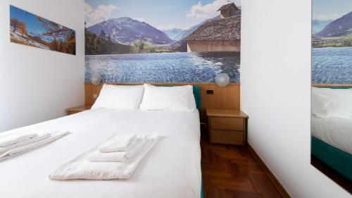a bedroom with a white bed with a painting on the wall at Italianway - San Giovanni 13/A in Bormio