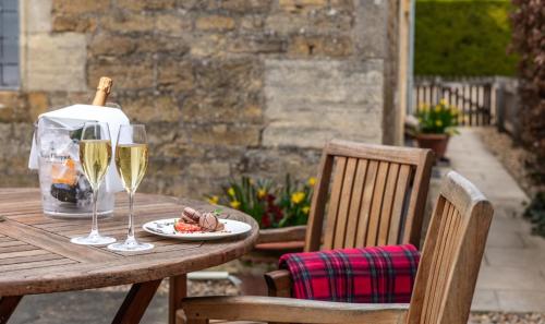 a table with two glasses of wine and a plate of food at The Lygon Arms - an Iconic Luxury Hotel in Broadway