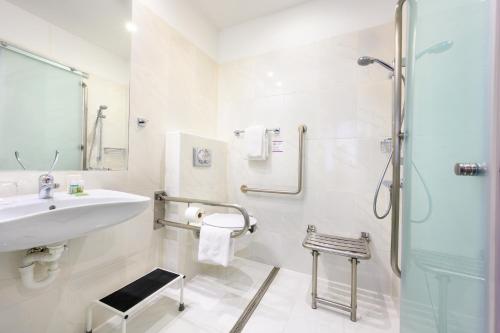 a white bathroom with a sink and a shower at Roombach Hotel Budapest Center in Budapest