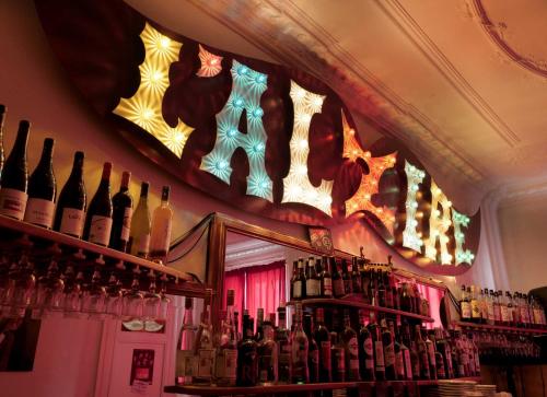 un bar avec un tas de bouteilles de vin dans l'établissement L'Alzire - Logis Auberge Culturelle, à Jarnages