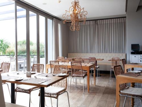 een eetkamer met tafels en stoelen en een kroonluchter bij Atlantic Beach Hotel in Melkbosstrand