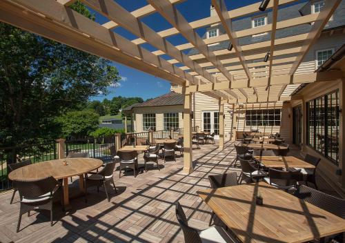 an outdoor patio with tables and chairs and a wooden pergola at Boar's Head Resort in Charlottesville