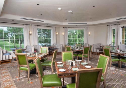 a restaurant with wooden tables and green chairs at Boar's Head Resort in Charlottesville