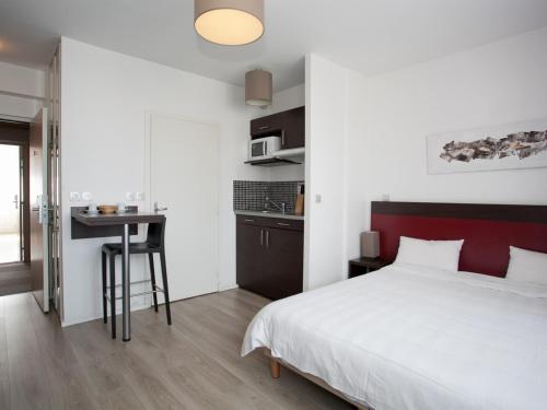 Schlafzimmer mit einem weißen Bett und einem Schreibtisch in der Unterkunft Residhotel Lille Vauban in Lille