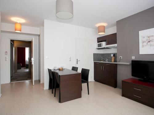 a living room with a dining room table and a kitchen at Residhotel Lille Vauban in Lille