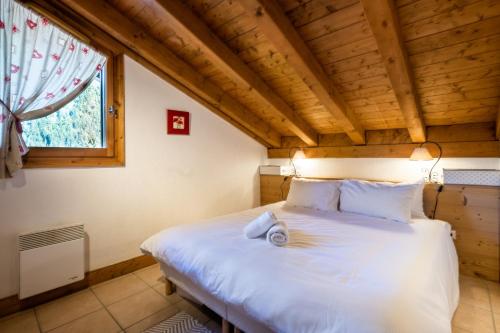ein Schlafzimmer mit einem großen weißen Bett in einem Zimmer mit einem Fenster in der Unterkunft Glacier - Les Amethystes in Les Houches