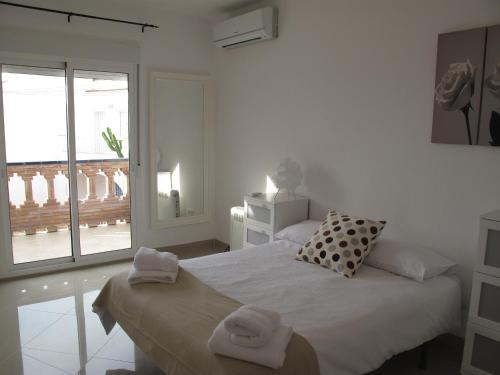 een witte slaapkamer met een bed met twee handdoeken erop bij Hernan Cortes in Nerja
