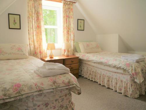 a bedroom with two beds and a window at Rowan Cottage in New Galloway