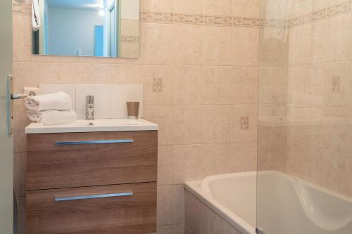 une salle de bain avec un lavabo et une baignoire dans l'établissement Le Reflet Citadin - 1 Chambre, à Brive-la-Gaillarde