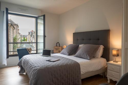 une chambre avec un lit avec un ordinateur portable dessus dans l'établissement Le Reflet Citadin - 1 Chambre, à Brive-la-Gaillarde