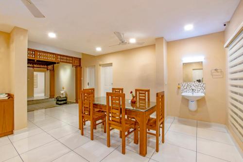ein Esszimmer mit einem Tisch, Stühlen und einem Waschbecken in der Unterkunft Sanskriti in Thiruvananthapuram