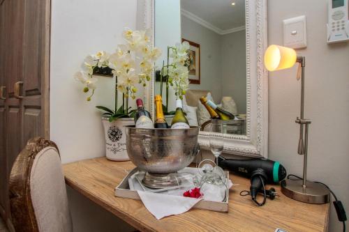 a table with a bowl of wine bottles and a mirror at Sandals Guest House in Durban