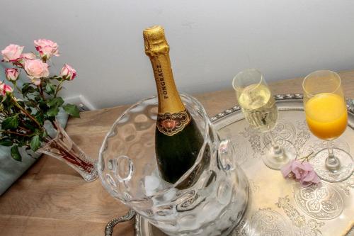 a bottle of champagne in a crystal bucket on a table with glasses at Sandals Guest House in Durban