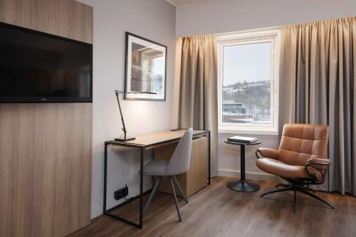 a hotel room with a desk and a chair and a television at Radisson Blu Hotel Nydalen, Oslo in Oslo