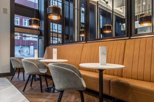 two tables and chairs in a restaurant with windows at Radisson Blu Hotel Prague in Prague