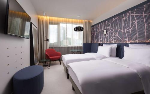 a hotel room with two beds and a red chair at Radisson Blu Hotel Lietuva in Vilnius